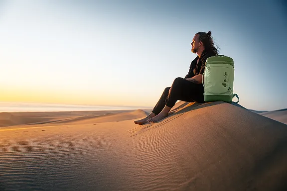 Abenteurer mit Gepäck auf einer Düne